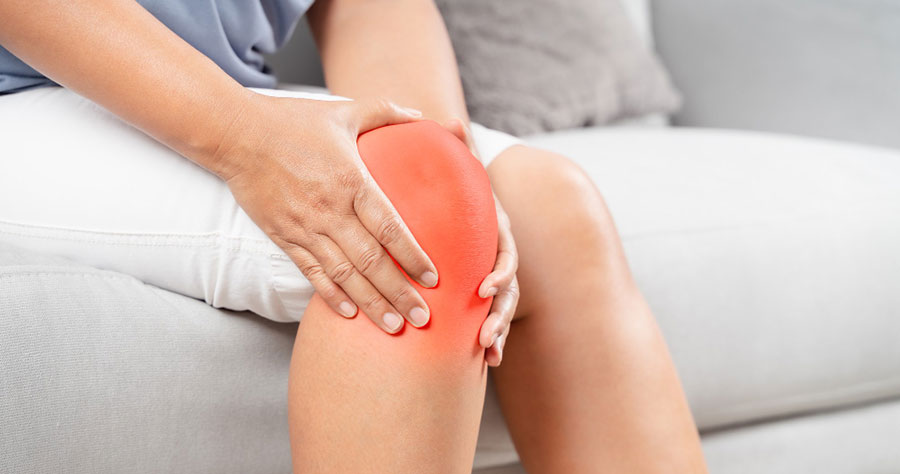 Osoba drži ruku preko kolena sa crvenim označenim područjem koje ukazuje na bol u kolenu.